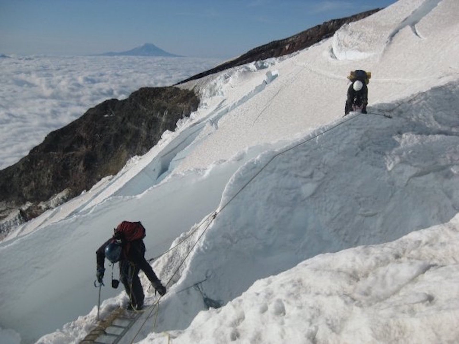 Climbers crossing crevasse on Mt. Rainier in Washington State.